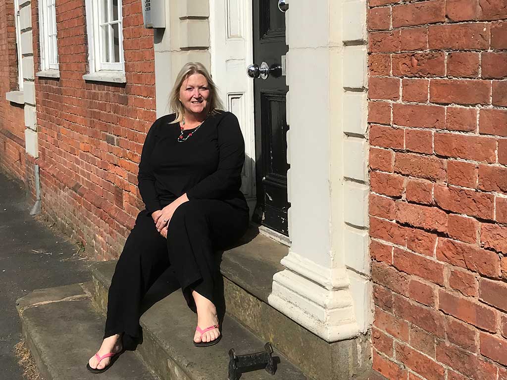 Picture of Karen Constantine sat outside a former mother and baby home in Coleshill, West Midlands.
